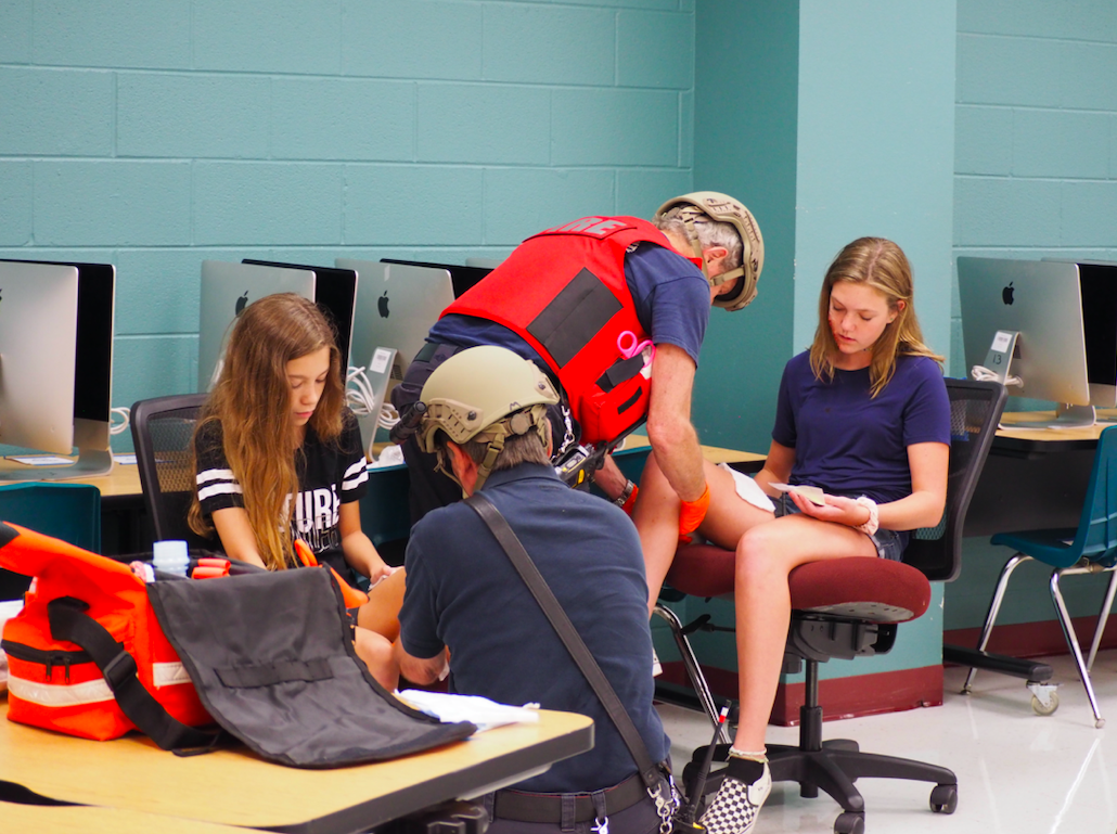 Members of North Hays Fire/Rescue treat simulated injuries. Students Mikaela Schelling (left- black shirt) and Reese Levinson (right-blue shirt) play roles of injured, complete with make-up and symptoms. During the process they are provided security by various deputies and constable officers in what is called a warm zone.